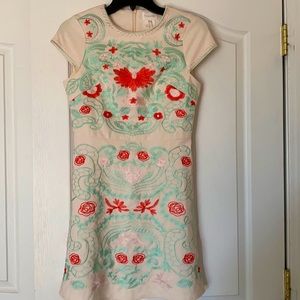 Cream dress with turquoise embroidery details.